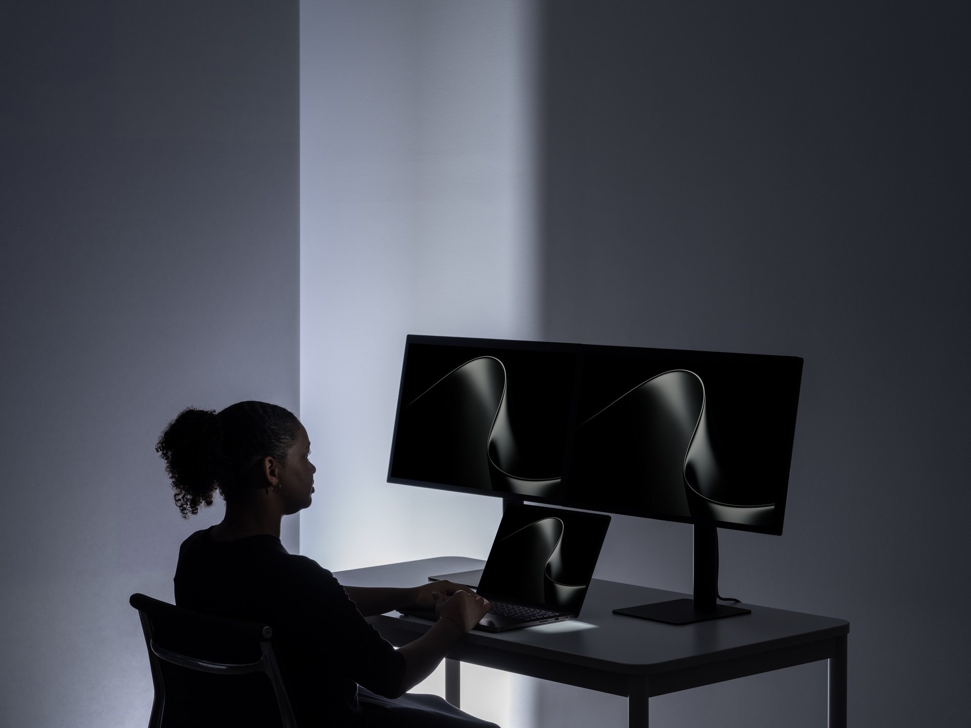 A creator working at a Surface Laptop Ultra and two external displays